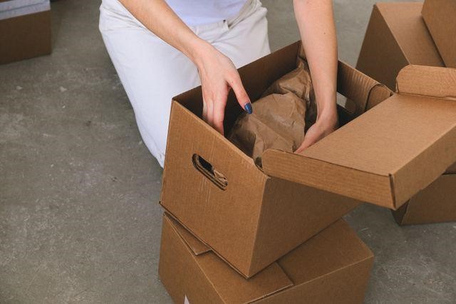 a person packing a cardboard box